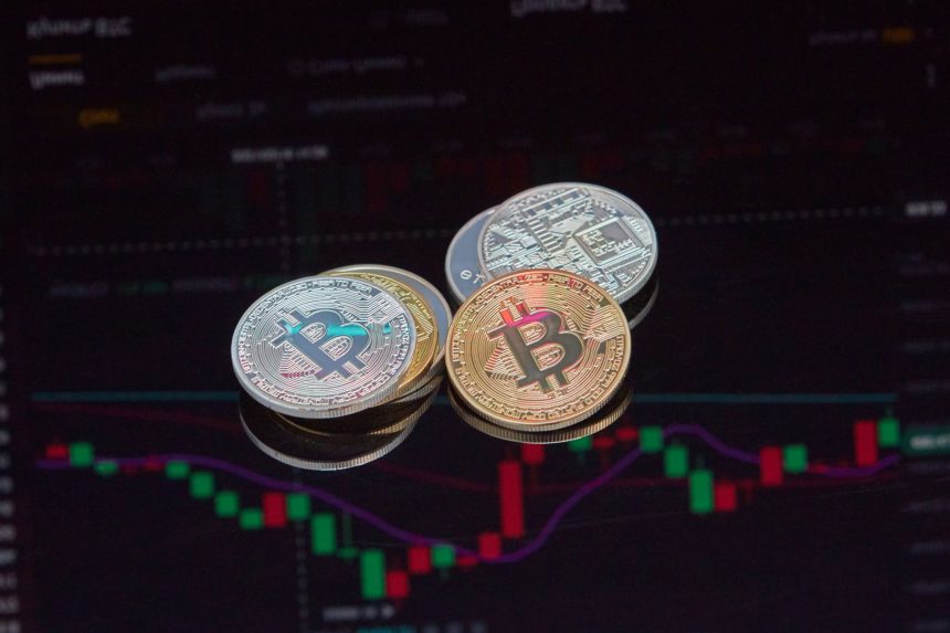 Moedas de Bitcoin em primeiro plano sobre um gráfico de mercado financeiro.